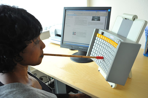 a woman using a mouth stick to interact with a vertical keyboard